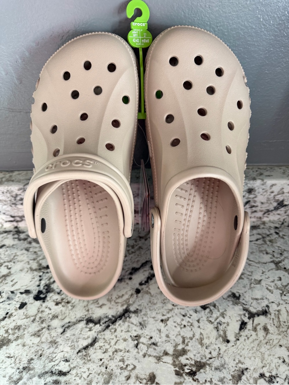 Beige Crocs Baya Clogs featuring a pivoting heel strap and ventilation holes.